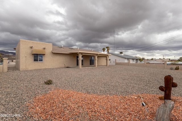 back of property with fence and stucco siding