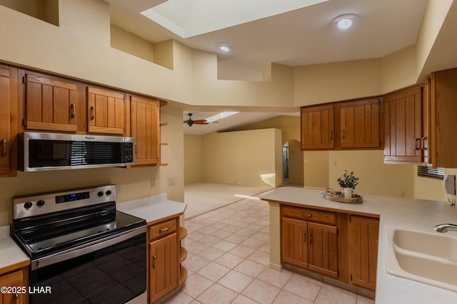 kitchen featuring open floor plan, light countertops, appliances with stainless steel finishes, a ceiling fan, and a sink