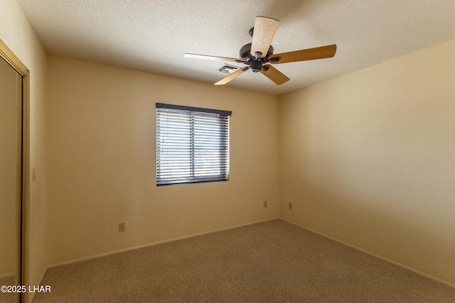 spare room with a ceiling fan, baseboards, visible vents, carpet floors, and a textured ceiling