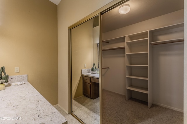 bathroom featuring vanity, a walk in closet, and baseboards