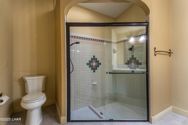 bathroom featuring a shower stall, toilet, and baseboards