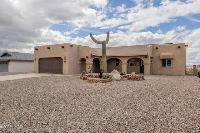 southwest-style home with a garage, driveway, and stucco siding