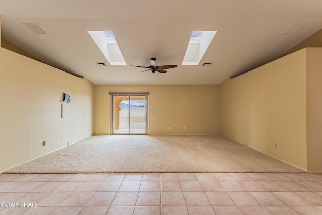 unfurnished room featuring light tile patterned floors, visible vents, light colored carpet, and ceiling fan