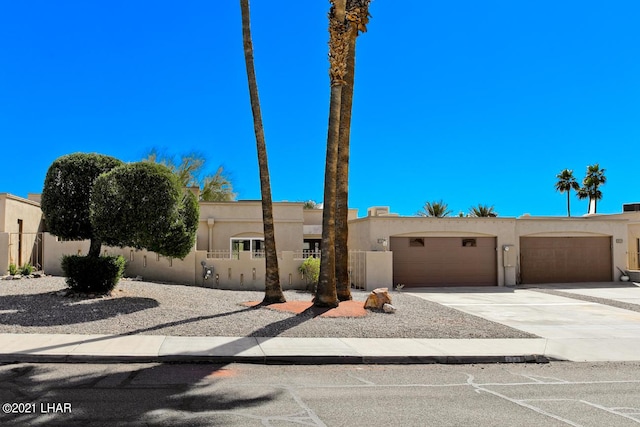 view of front facade featuring a fenced front yard, concrete driveway, an attached garage, and stucco siding