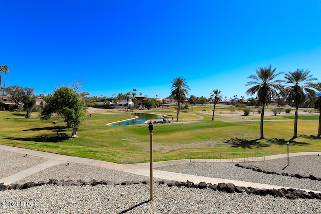 view of home's community with a water view, view of golf course, and a lawn