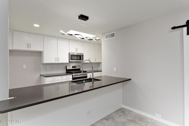 kitchen with appliances with stainless steel finishes, dark countertops, visible vents, and a barn door