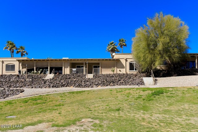 rear view of house featuring a yard and stucco siding