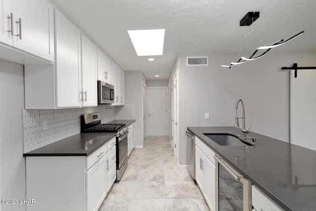 kitchen featuring stainless steel appliances, dark countertops, visible vents, white cabinets, and a sink