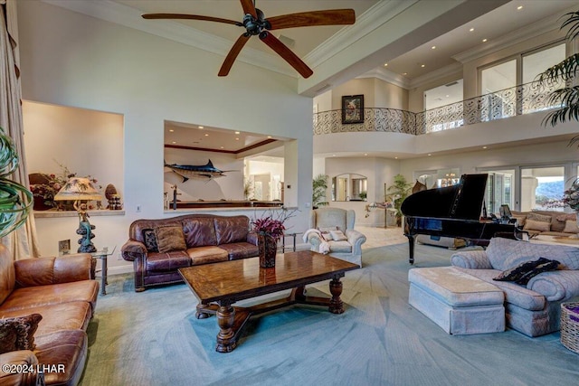 living room featuring ceiling fan, ornamental molding, carpet, and a towering ceiling