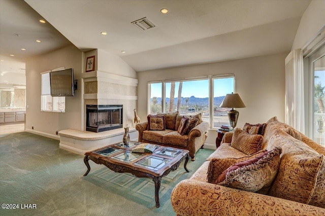 living room featuring a tile fireplace, carpet floors, and lofted ceiling