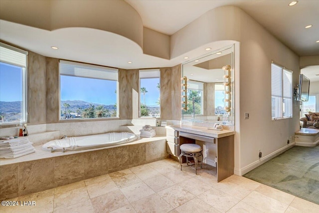 bathroom with a mountain view, tiled tub, and a healthy amount of sunlight