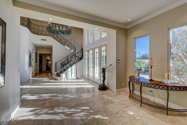 entrance foyer with a towering ceiling, crown molding, and plenty of natural light