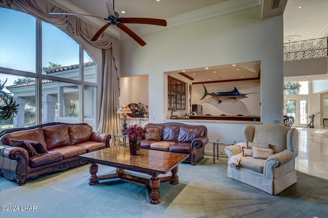 living room with crown molding, tile patterned flooring, a towering ceiling, and ceiling fan