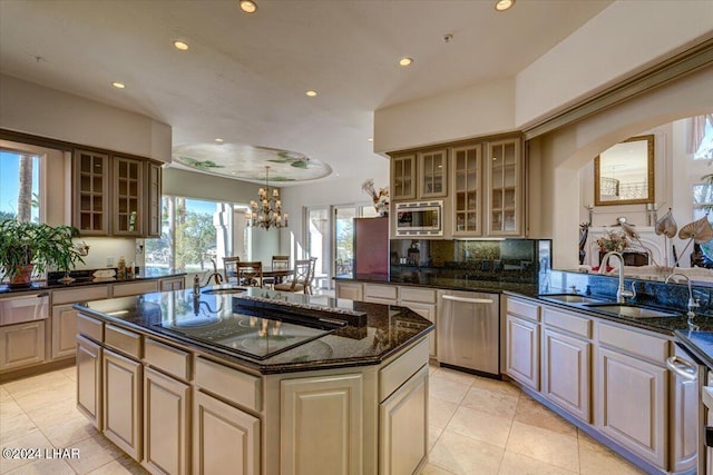 kitchen featuring tasteful backsplash, stainless steel appliances, dark stone counters, a center island, and sink