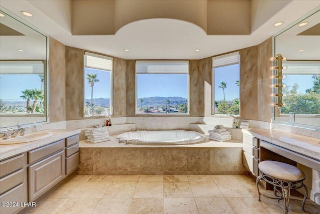 bathroom with tiled bath, a mountain view, vanity, and a healthy amount of sunlight