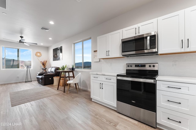 kitchen featuring tasteful backsplash, light hardwood / wood-style floors, white cabinets, and appliances with stainless steel finishes