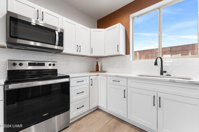 kitchen featuring tasteful backsplash, white cabinetry, appliances with stainless steel finishes, and sink