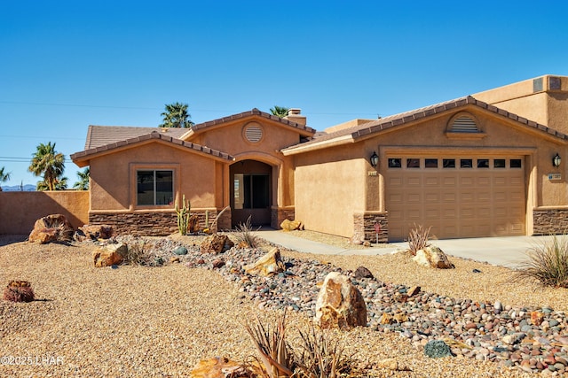 view of front of property with stucco siding, concrete driveway, an attached garage, stone siding, and a tiled roof