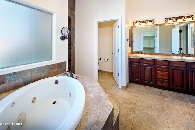 bathroom with toilet, a sink, a whirlpool tub, and double vanity