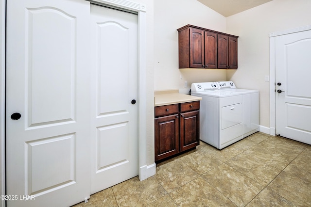 clothes washing area with washing machine and dryer, cabinet space, and baseboards