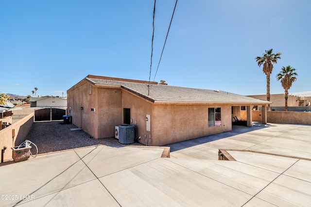 exterior space with a tile roof, stucco siding, a patio area, central AC, and fence