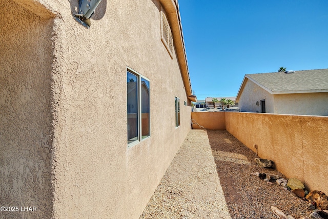 view of side of property featuring fence and stucco siding