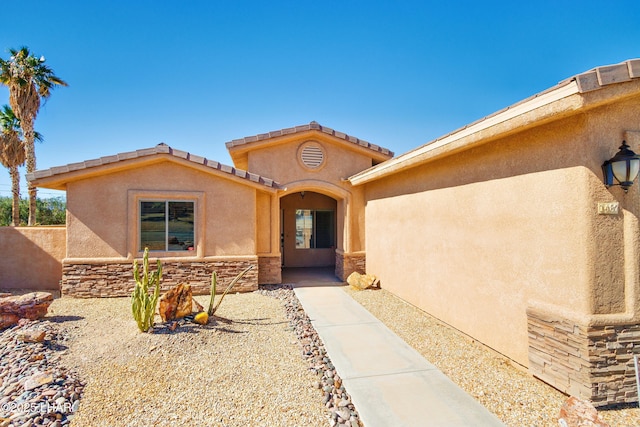 doorway to property with stone siding and stucco siding