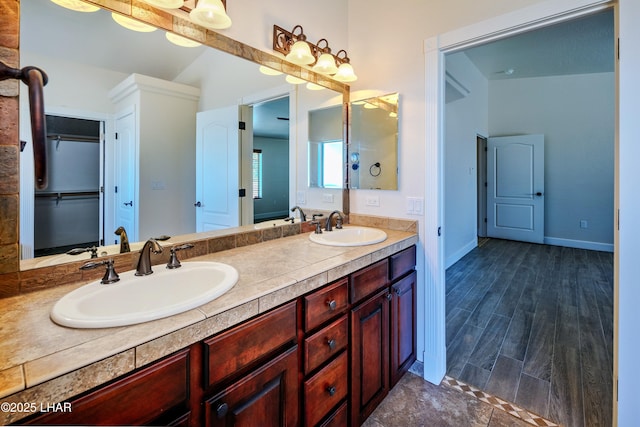 full bathroom featuring double vanity, wood finished floors, a sink, and baseboards