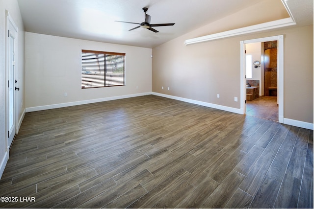 empty room featuring lofted ceiling, dark wood-style floors, baseboards, and a ceiling fan