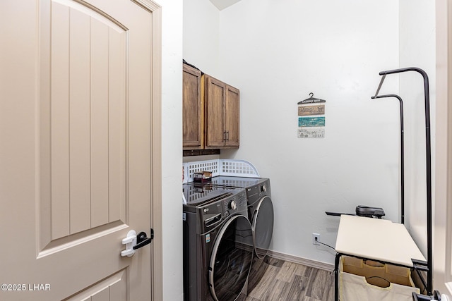 laundry room with wood finished floors, baseboards, cabinet space, and washing machine and dryer