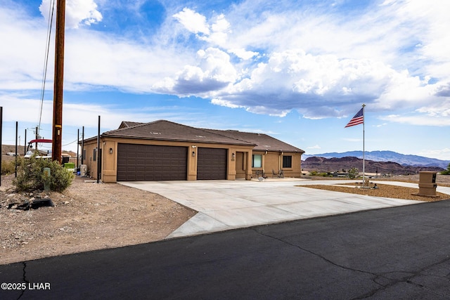 view of front of house featuring an attached garage, a tile roof, stucco siding, a mountain view, and driveway
