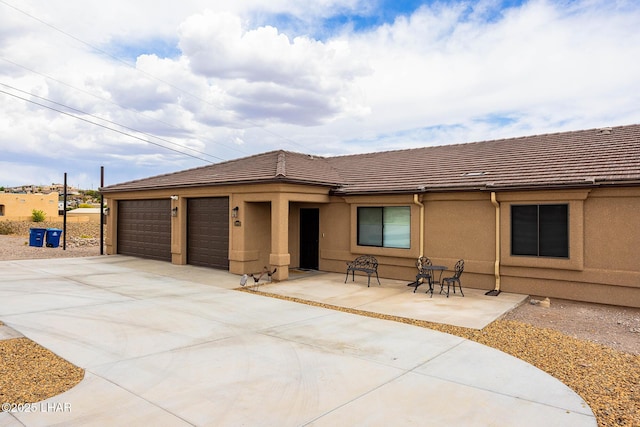 view of front of house with a garage, stucco siding, a tiled roof, and driveway