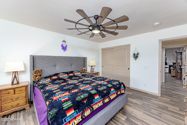 bedroom with a ceiling fan, baseboards, wood finished floors, and a closet