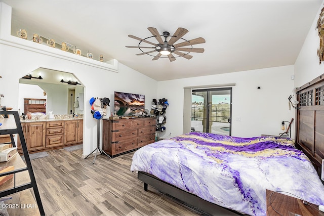 bedroom featuring access to outside, connected bathroom, a ceiling fan, light wood finished floors, and vaulted ceiling
