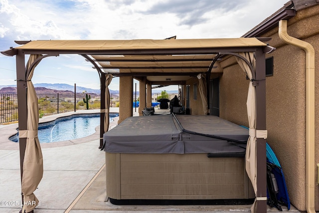 view of swimming pool with a hot tub, fence, a fenced in pool, a mountain view, and a patio