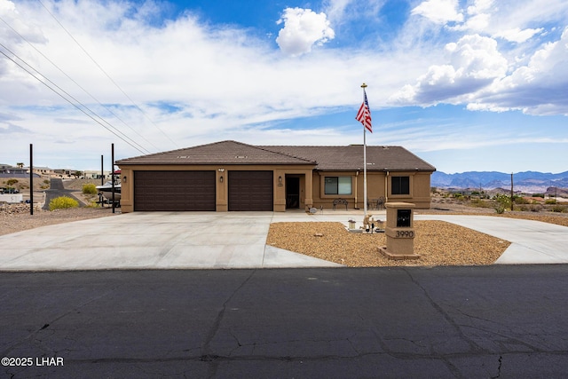 ranch-style home with stucco siding, a tiled roof, concrete driveway, an attached garage, and a mountain view