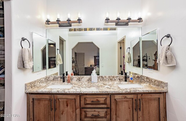 ensuite bathroom with double vanity, a sink, and connected bathroom