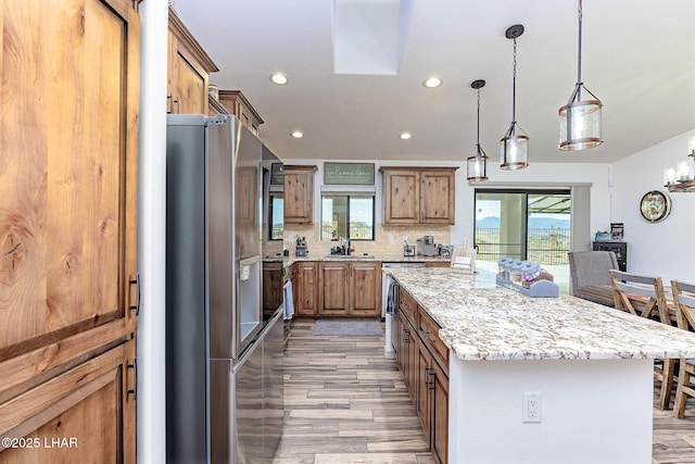 kitchen featuring decorative backsplash, light wood-style floors, a center island, recessed lighting, and appliances with stainless steel finishes