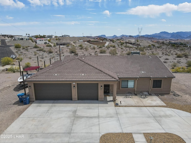 ranch-style house with a garage, stucco siding, a tiled roof, a mountain view, and driveway