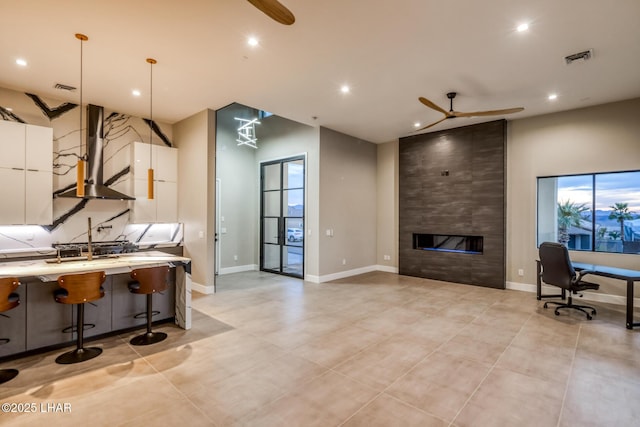 kitchen featuring white cabinetry, a kitchen breakfast bar, ceiling fan, and pendant lighting