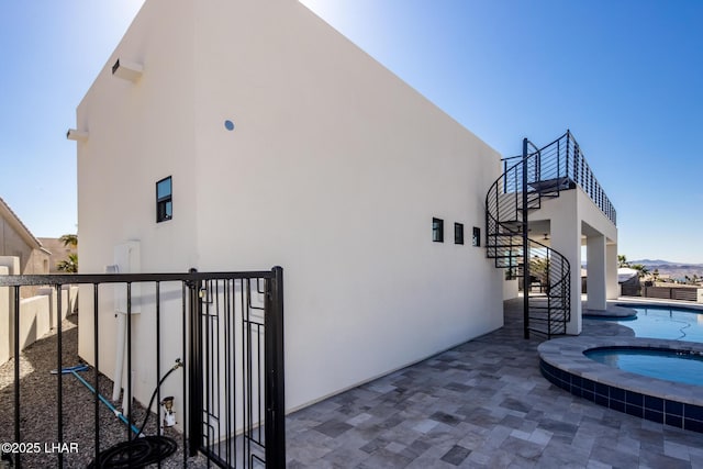 view of side of home featuring a patio area, a mountain view, and a pool with hot tub