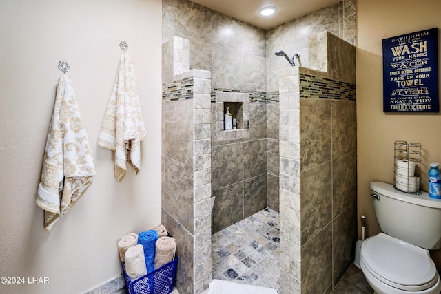 bathroom featuring a tile shower and toilet