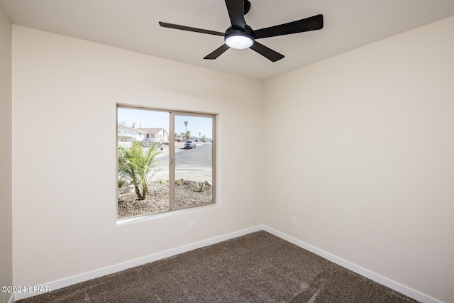 empty room featuring baseboards, a ceiling fan, and dark colored carpet