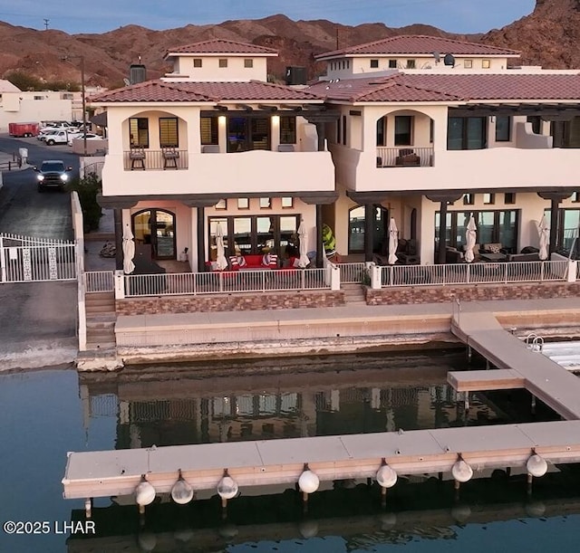 back of property featuring a water and mountain view and a balcony