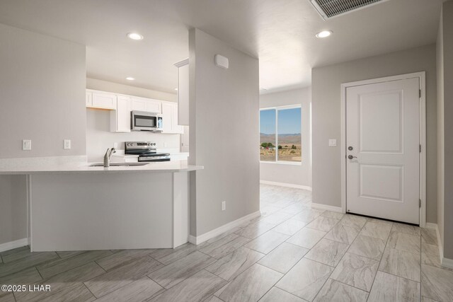 9342 N Broken Saddle Dr, Kingman, AZ 86401 - kitchen featuring appliances with stainless steel finishes, light countertops, white cabinetry, recessed lighting, and a peninsula
