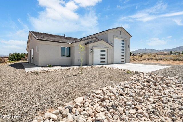 9342 N Broken Saddle Dr, Kingman, AZ 86401 - view of front of house featuring driveway, a garage, a mountain view, and stucco siding