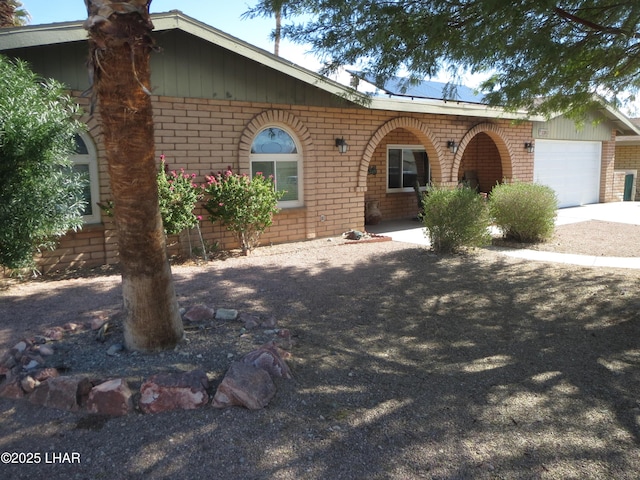 view of front of house featuring a garage, concrete driveway, and brick siding