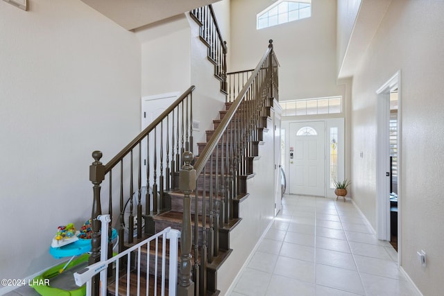 foyer entrance featuring light tile patterned floors, a high ceiling, and baseboards