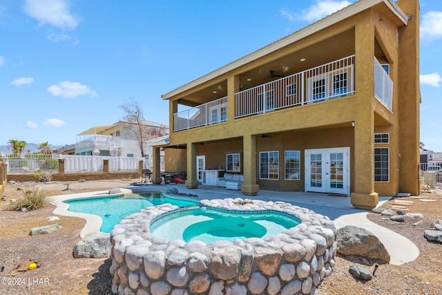 back of house with a balcony, fence, a ceiling fan, french doors, and stucco siding