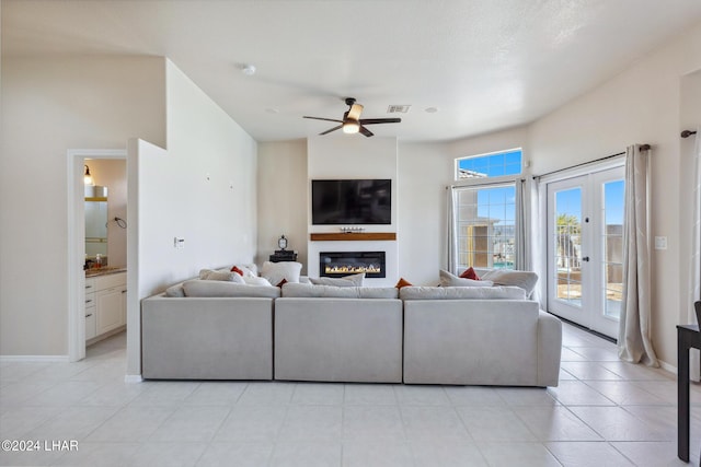 living room featuring baseboards, visible vents, a ceiling fan, a glass covered fireplace, and french doors